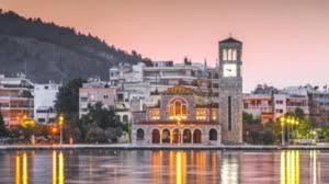 a building with a clock tower in front of a city at Alkistis House in Volos