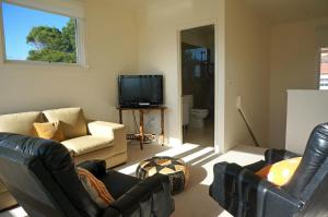 a living room with leather furniture and a tv at Rip Tide in Point Lonsdale