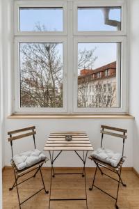 dwa krzesła i stół w pokoju z dwoma oknami w obiekcie Apartment für 10 Gäste, 2 Bäder, 2 Loggia's, Leipzig Zentrum Ost w Lipsku