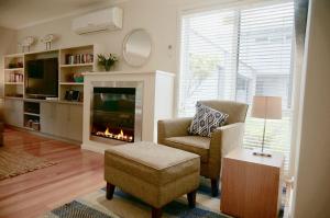 a living room with a fireplace and a chair at Beachcomber in Point Lonsdale