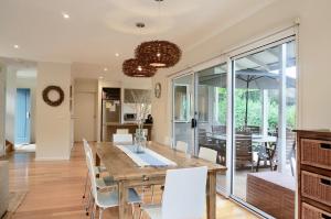 a dining room with a wooden table and white chairs at Beachcomber in Point Lonsdale