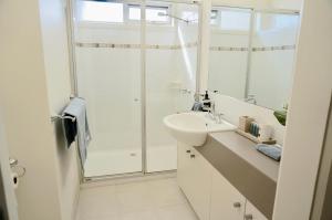 a white bathroom with a sink and a shower at Beachcomber in Point Lonsdale +9 photos