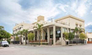 a white building with palm trees in front of it at Catalina Hotel San Pedro de Jujuy in San Pedro de Jujuy