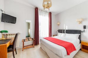 Dormitorio con cama, escritorio y TV en Crystal Hotel, en Levallois-Perret