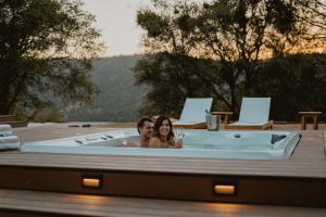 a man and woman sitting in a bath tub at Boho chic oasis by Casa Oso with pool, spa and views in Ahwahnee