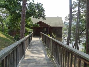 eine Brücke, die zu einer Hütte im Wald führt in der Unterkunft C14, Two bedroom, two bath, log-sided, luxury Harbor North cottage overlooking the lake, cottage in Mount Ida