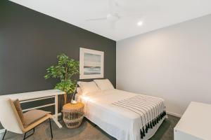 une chambre avec un lit blanc et une chaise dans l'établissement Sunfish Special - Beachside Townhouse by uHoliday, à Kingscliff 4 autres photos