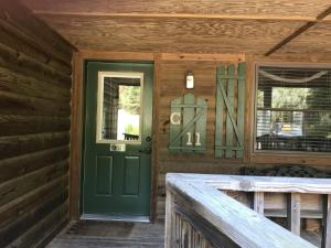 - une porte verte à l'avant d'une maison en bois dans l'établissement C11, Two bedroom, two bath log-sided, luxury Harbor North cottage with hot tub cottage, à Mount Ida