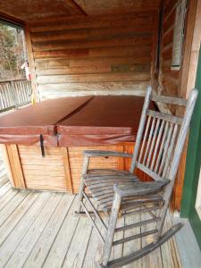 a rocking chair sitting on the porch of a cabin at Luxury, loft, log-sided two bedroom Harbor North cottage cottage in Mount Ida