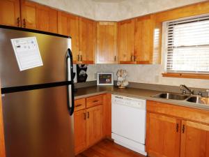 a kitchen with a stainless steel refrigerator and wooden cabinets at Luxury, loft, log-sided two bedroom Harbor North cottage cottage in Mount Ida