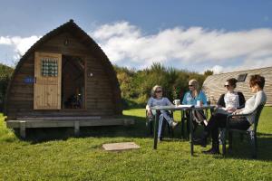 a group of people sitting at a table in front of a cabin at Pot a Doodle Do in Berwick-Upon-Tweed