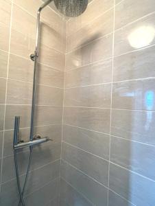 a shower in a bathroom with a tiled wall at Studio Cosy et fonctionnel drancy CDG in Drancy