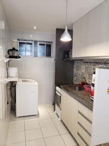 a white kitchen with a sink and a refrigerator at Ap próx shopping aeroporto in Recife