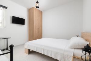a white bedroom with a bed and a cabinet at Άνετο διαμέρισμα με κήπο in Rhodes Town