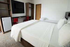 un letto bianco in una camera d'albergo con TV di GH Hotel Express a Juiz de Fora