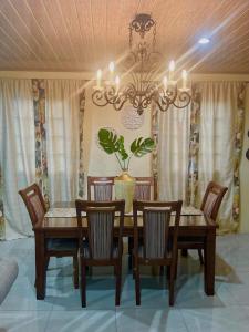 uma sala de jantar com uma mesa e cadeiras e um lustre em Pearls Place em Arima
