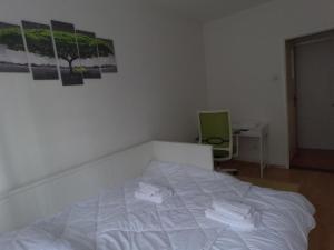 uma cama branca num quarto com duas fotografias na parede em Folka cozy apartment em Zagreb