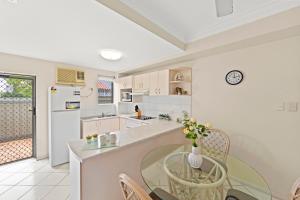Koala Court Holiday Apartments في كيرنز: مطبخ مع طاولة زجاجية مع إناء من الزهور