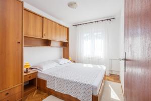 a small bedroom with a bed and wooden cabinets at Apartments by the sea Grebastica, Sibenik - 11463 in Grebaštica