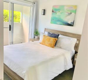 a bedroom with a bed with white sheets and pillows at Pandanus Pocket 3BR Beachside Condo by uHoliday in Casuarina +11 photos