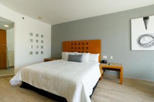 Un dormitorio con una gran cama blanca y una mesa en Real Inn Torreon, en Torreón