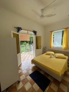 Un dormitorio con una cama amarilla y una ventana en Charmante maison, en Deshaies