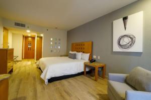 Real Inn Torreon في توريون: غرفه فندقيه بسرير واريكه