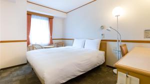 Toyoko Inn Chiba Ekimae في شيبا: غرفه فندقيه سرير ابيض ونافذه