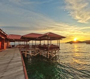 Coriana Dive Resort في Waisai: مرسى مع مطعم على الماء وقت الغروب