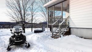 a snowmobile parked next to a house in the snow at Les Chalets Tourisma - Maison de campagne avec spa privé - La Familiale in Saint-Raymond