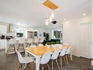 eine Küche und ein Esszimmer mit einem Holztisch und weißen Stühlen in der Unterkunft Les Chalets Tourisma - Maison de campagne avec spa privé - La Familiale in Saint-Raymond