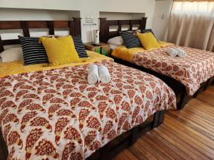 two beds with slippers on them in a bedroom at Edificio El Barrio Vertical in San José