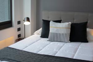 Una cama blanca con almohadas negras en un dormitorio en Punto Lofts Periférico Sur, en Ciudad de México