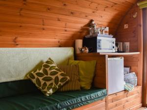 a green couch sitting in a room with a microwave at Rivendell Glamping Pod - Uk11881 in North Tamerton