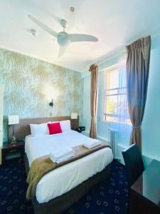 The Esplanade Hotel في أوكلاند: غرفة نوم مع سرير أبيض كبير مع وسائد حمراء