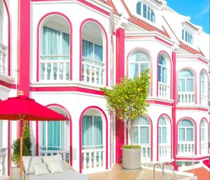 un edificio rosa y blanco con una sombrilla roja en Hotel Midtown Ratsada, en Phuket