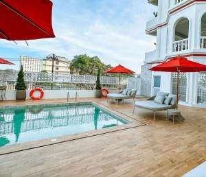 ein Pool auf dem Dach eines Hauses mit roten Sonnenschirmen in der Unterkunft Hotel Midtown Ratsada in Phuket
