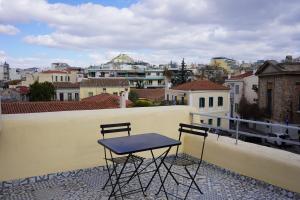 uma mesa e duas cadeiras sentadas numa varanda em A Painter's House in Plaka em Atenas