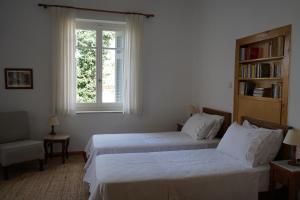 duas camas num quarto com uma janela e uma estante de livros em A Painter's House in Plaka em Atenas