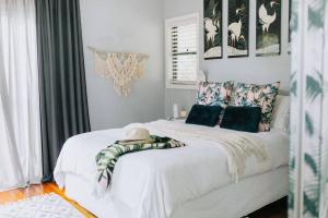 a bedroom with a white bed with blankets and pillows at Palm House - by Coast Hosting in Terrigal