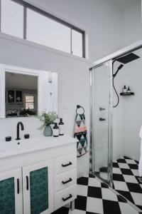 a bathroom with a sink and a shower with a mirror at Palm House - by Coast Hosting in Terrigal