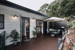 a house with a deck with a table and an umbrella at Palm House - by Coast Hosting in Terrigal