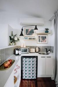 a kitchen with white cabinets and a bowl of fruit on the counter at Palm House - by Coast Hosting in Terrigal