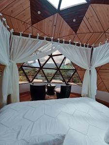 a bed in a room with a large window at Hotel Campestre La Periquera in Villa de Leyva