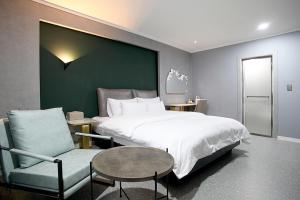 GimcheonBaba Hotel Gimcheon的带一张大床和一把椅子的卧室
