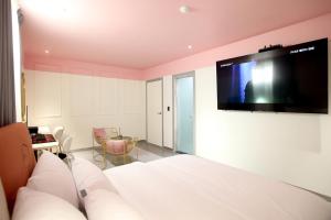a bedroom with a bed with a flat screen tv on the wall at Baba Hotel Gimcheon in Gimcheon