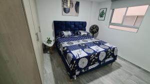 a bedroom with a blue bed and a window at Hermoso Apartamento Entero - Parqueadero - Ibague - Roble in Ibagué