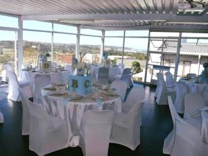 Cette chambre dispose de tables et de chaises blanches avec un gâteau. dans l'établissement GOODWILLMANOR, à Durban