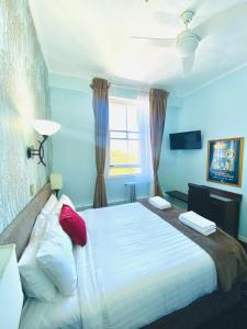 een slaapkamer met een groot wit bed met rode kussens bij The Esplanade Hotel in Auckland