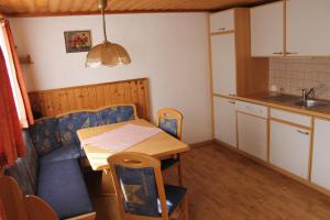eine kleine Küche mit einem Tisch und einem blauen Sofa in der Unterkunft Knappenhaus in Rauris